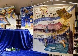 Un grupo de cuadros están colgados en una pared de una biblioteca.