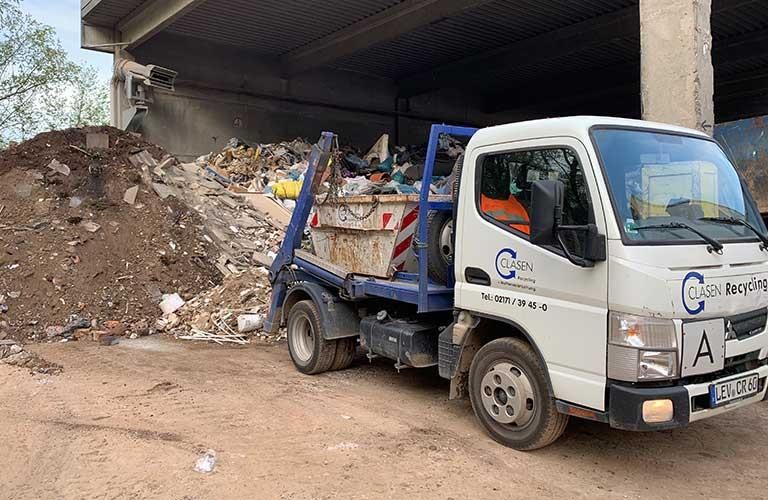 Ein Muldenkipper steht vor einem Müllhaufen.