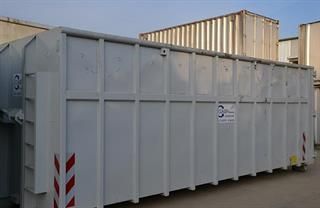 Vor einem Gebäude steht ein großer weißer Müllcontainer.