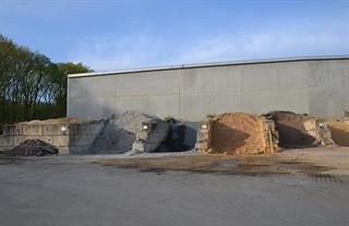 Vor einem Gebäude liegt ein großer Erdhaufen.