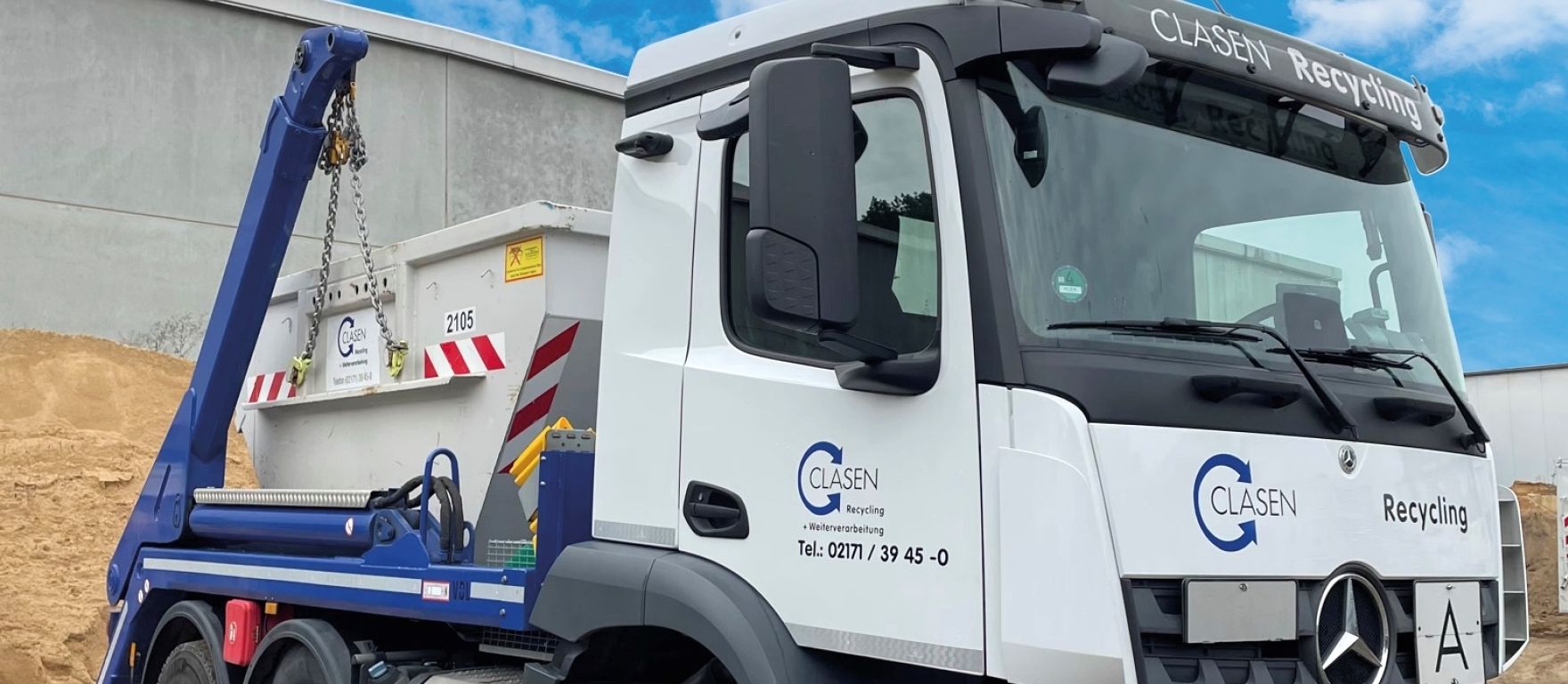 Ein weißer Muldenkipper mit einem daran befestigten blauen Kran