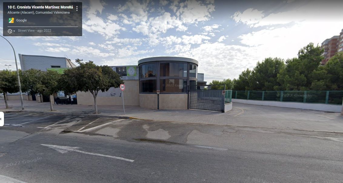 Un edificio está situado al costado de una carretera al lado de un estacionamiento.