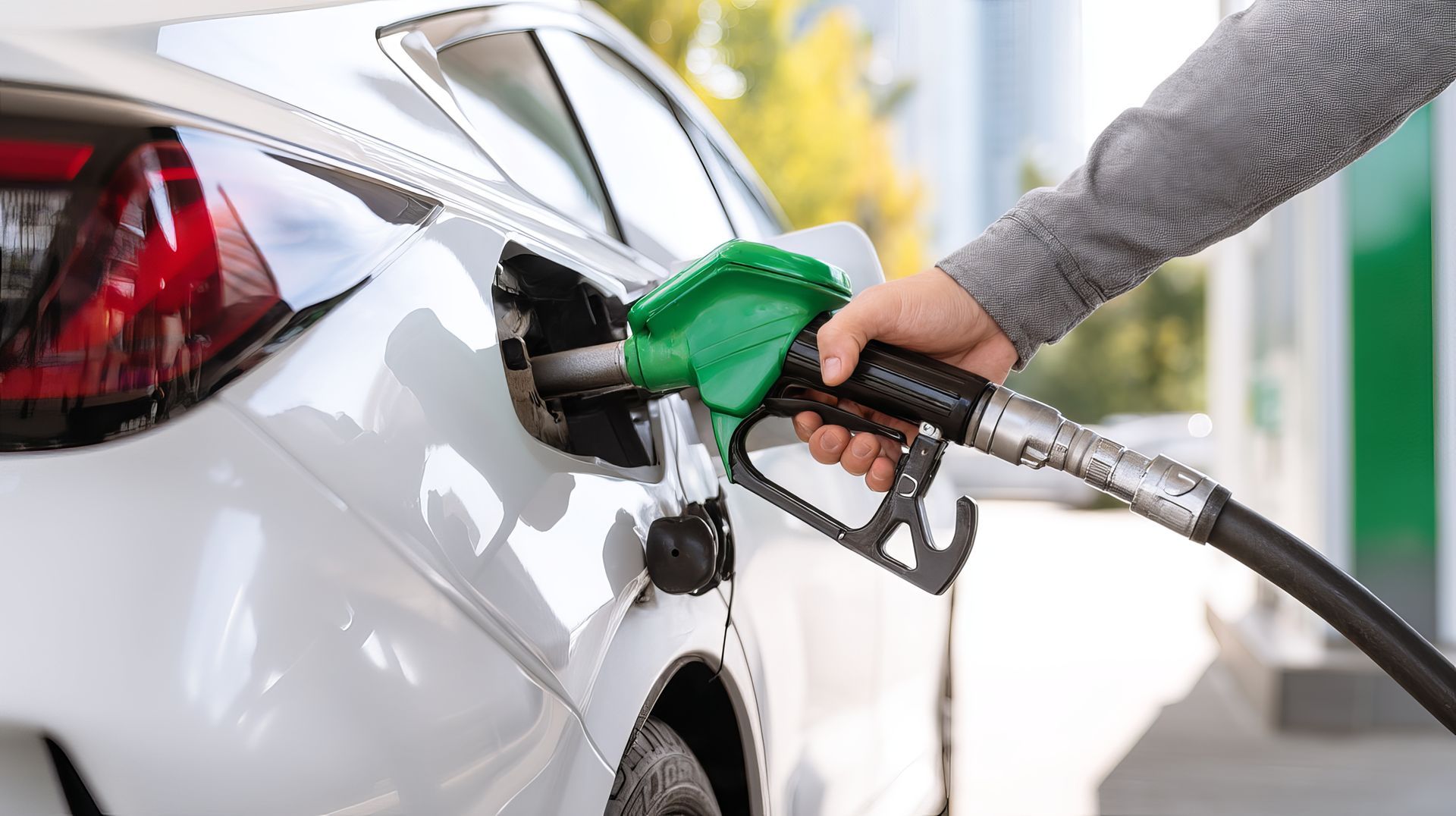 Main qui met du carburant dans une voiture blanche