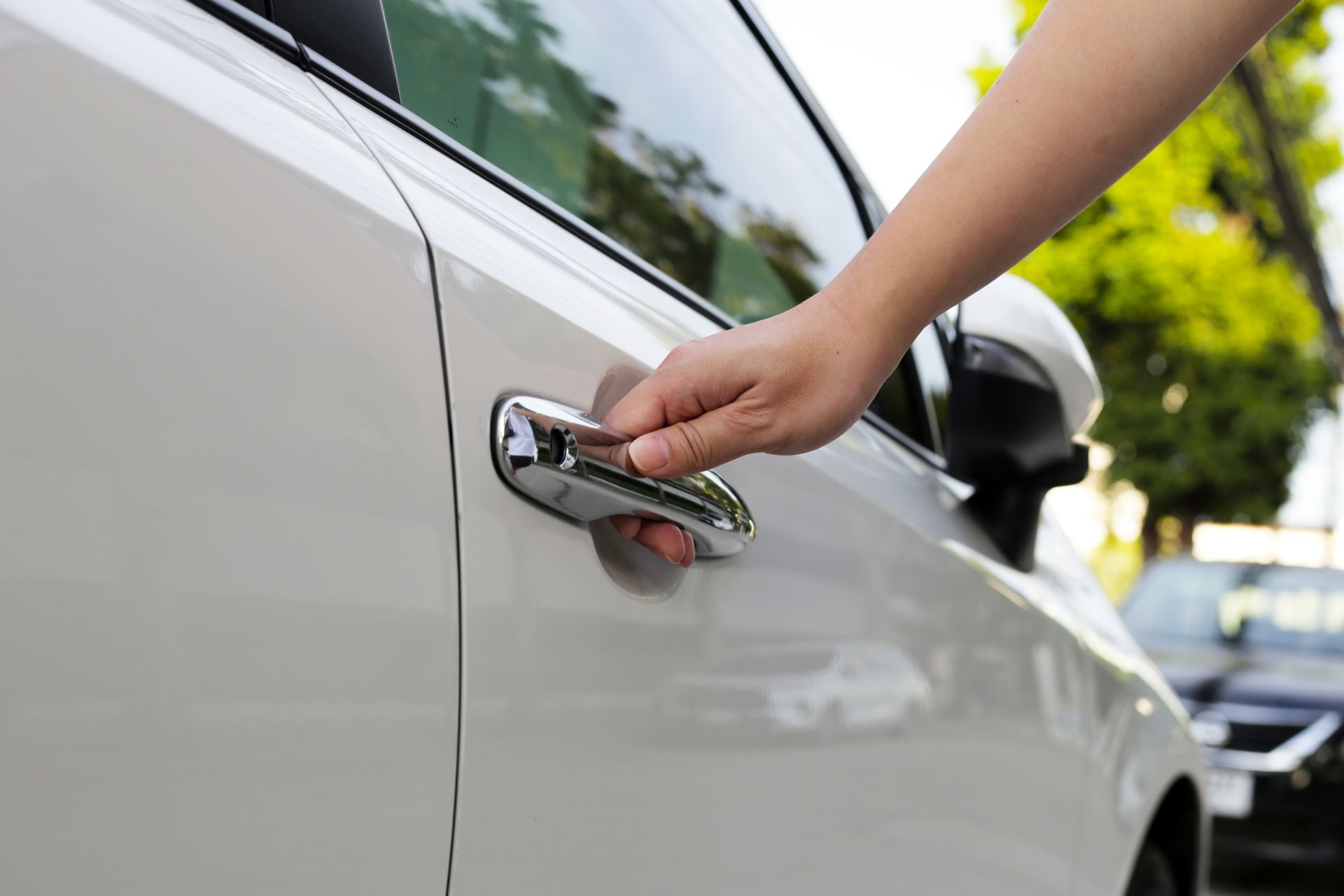 Main qui tient la poignée d'une voiture blanche