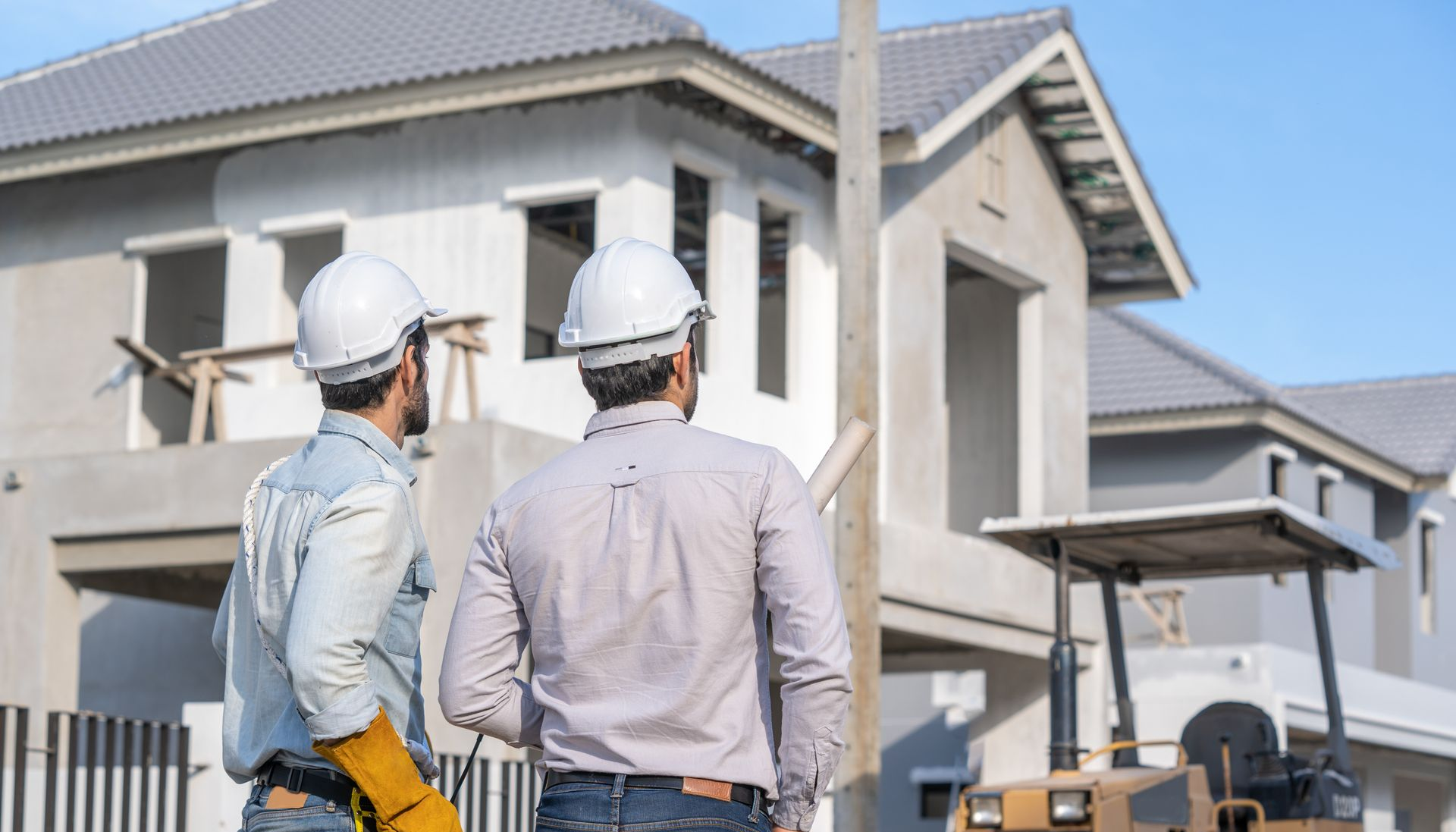 Deux hommes portant des casques de chantier inspectent une maison en construction.