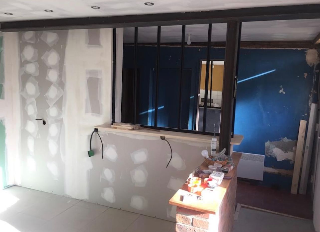 Rénovation intérieure avec cloisons sèches, ossature métallique noire et briques apparentes. Câbles électriques apparents.