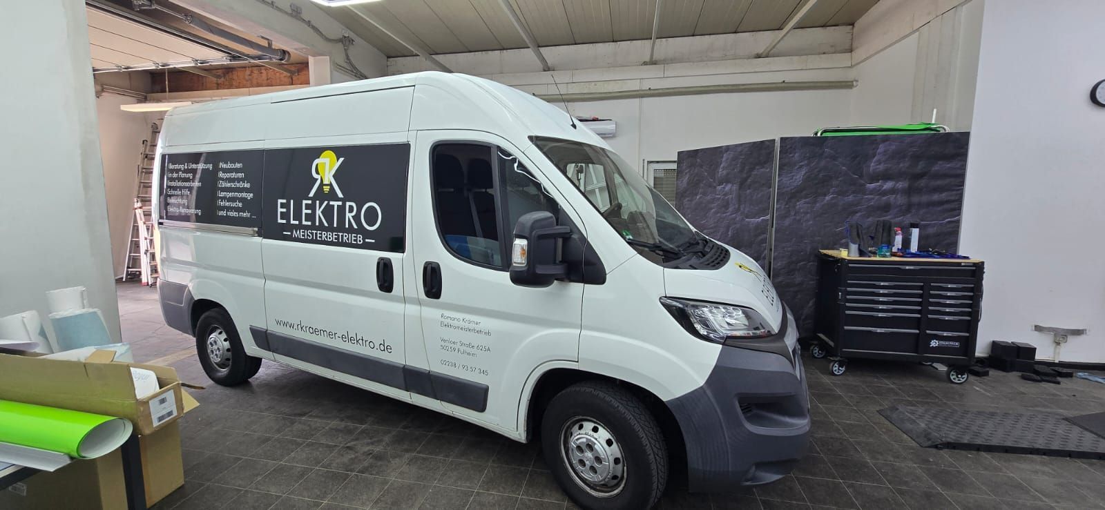 Ein Schutzhelm, ein Schraubenschlüssel, eine Wasserwaage und ein Werkzeugkasten liegen auf einem Holztisch.