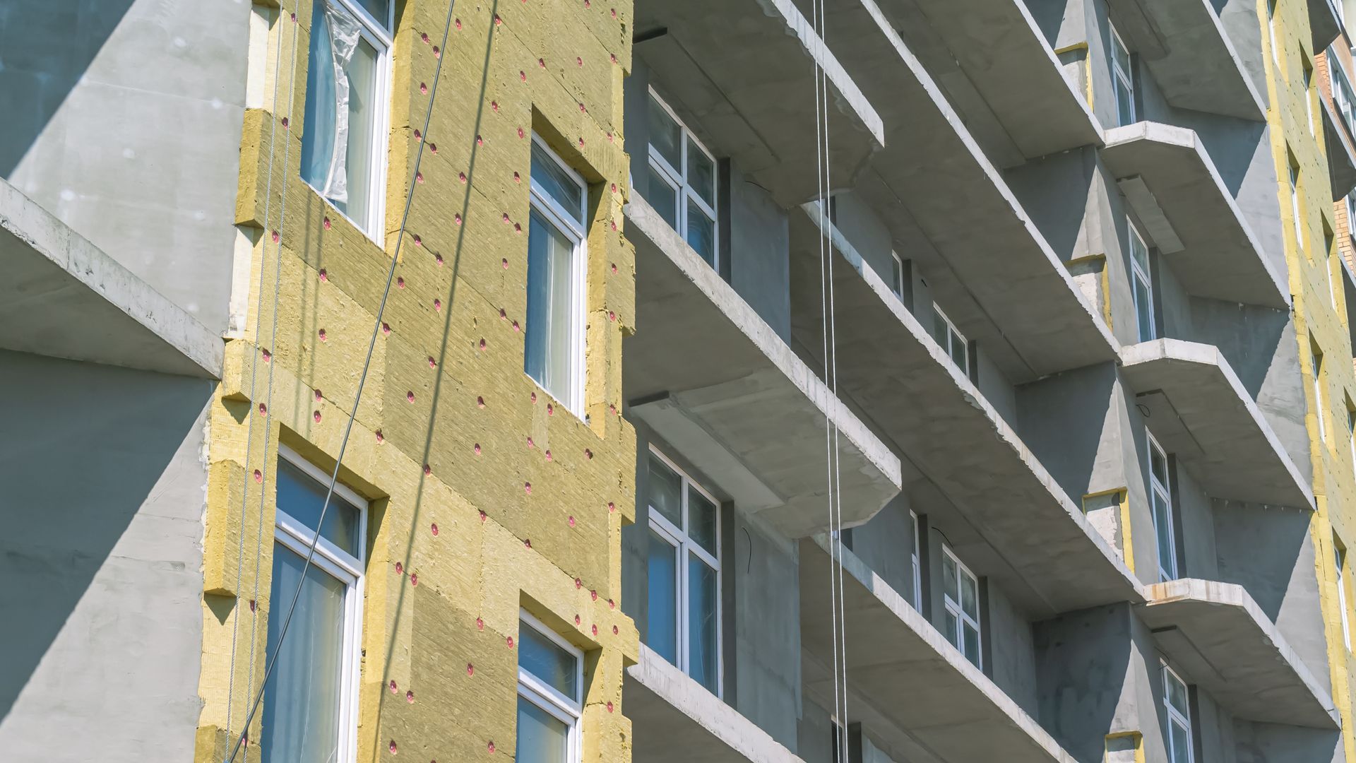 Esterno di un edificio in costruzione, che mostra l'isolamento e i balconi in cemento.