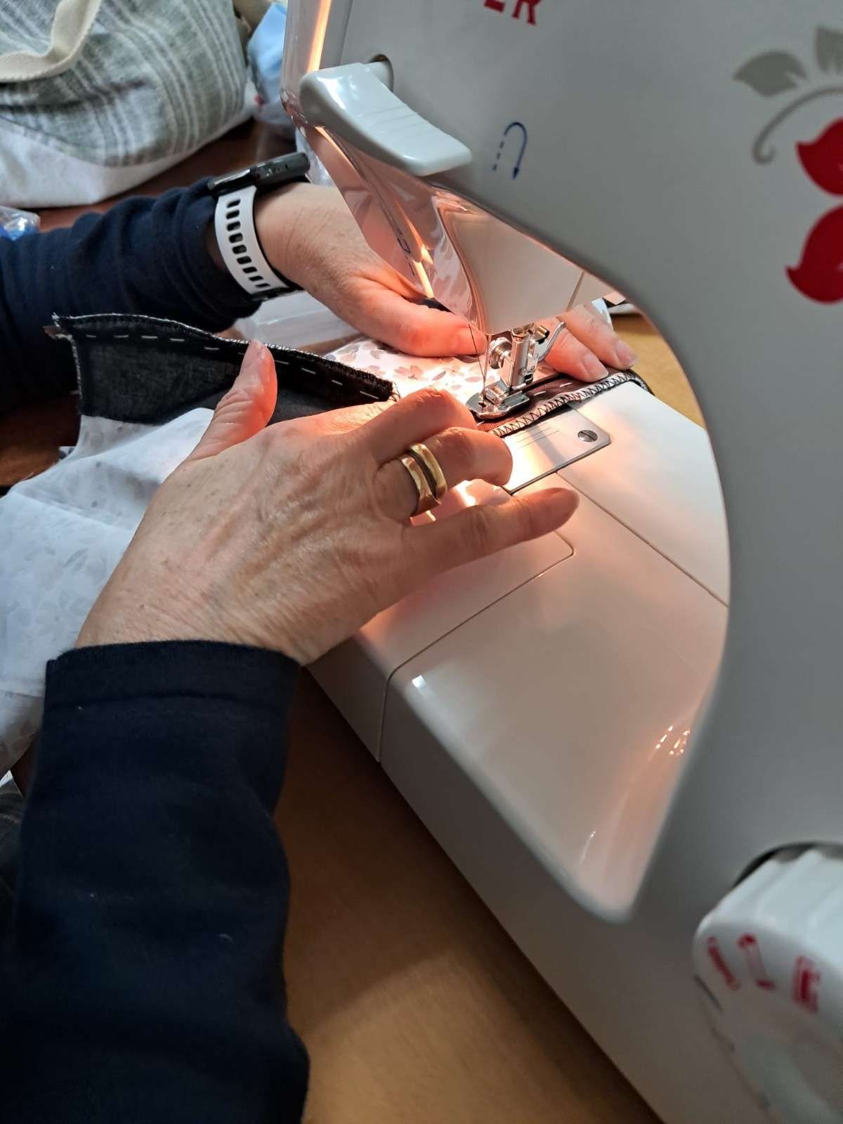 Las manos de una persona guían la tela a través de una máquina de coser.