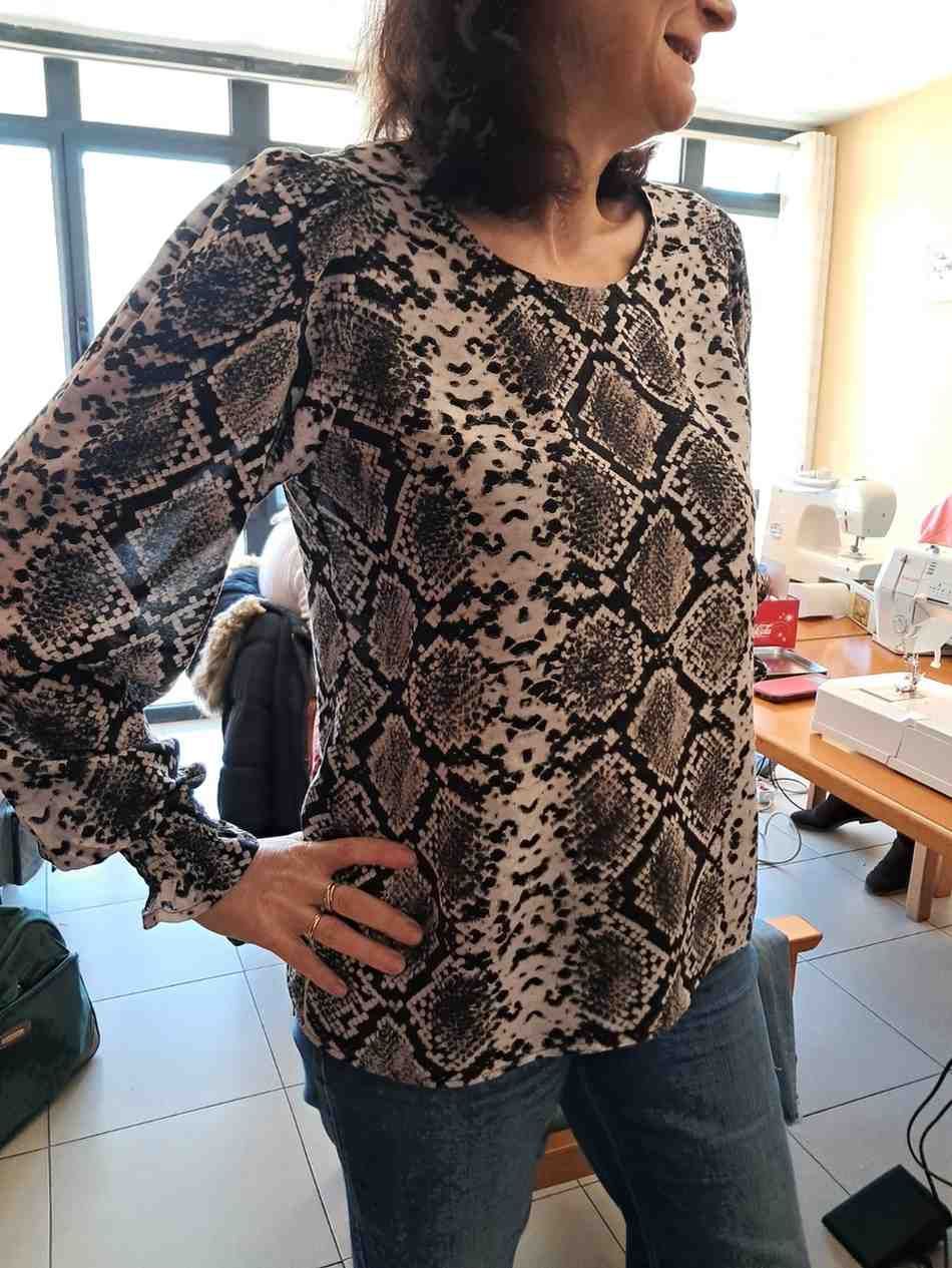 Una persona que lleva una blusa de manga larga con estampado de piel de serpiente y puños con volantes 