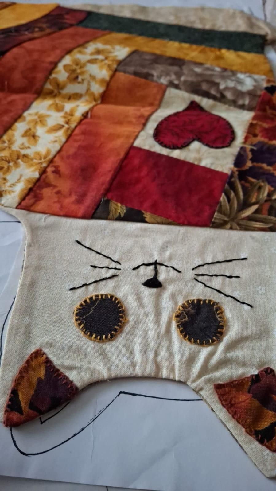 Una pequeña figurita de arcilla que representa a una bruja con un vestido morado y un sombrero negro montada en una escoba.