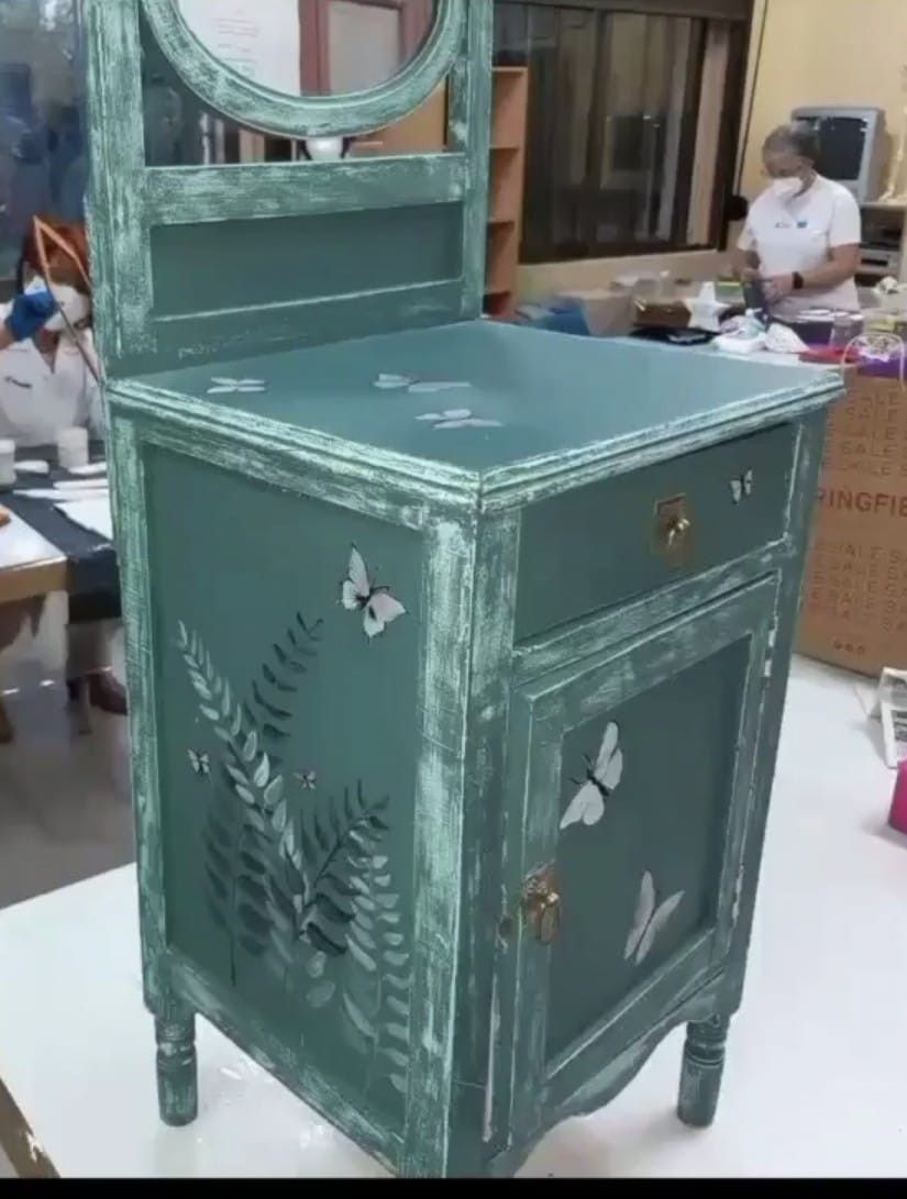 Una caja de manualidades gris con varios cajones, decorada con una ilustración de hadas y detalles florales.