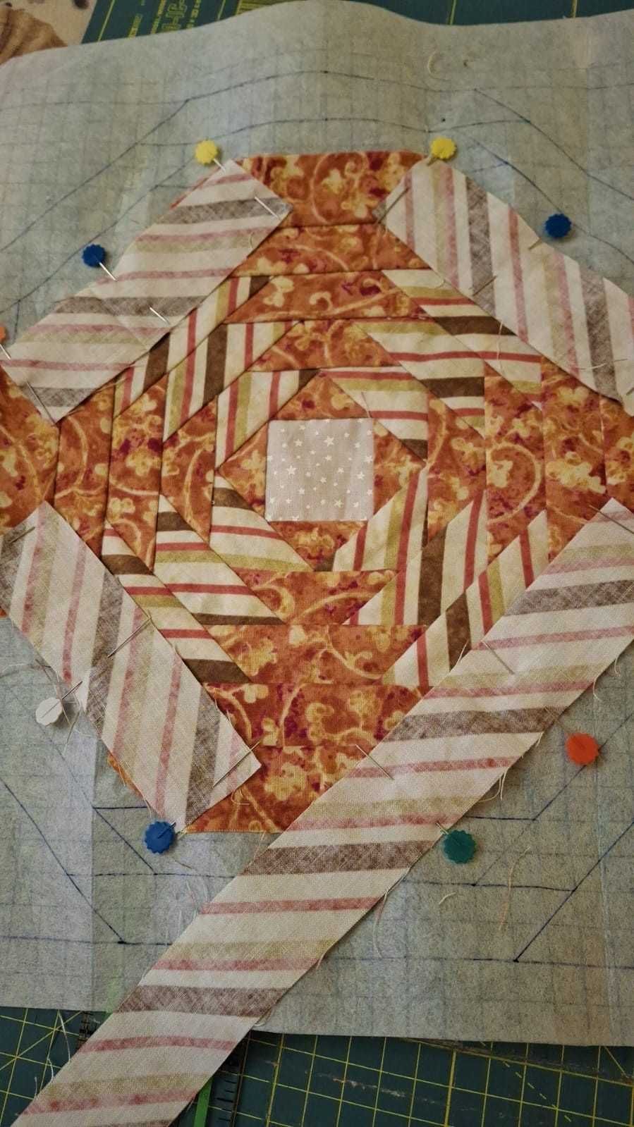 Una obra de arte enmarcada, realizada con técnica mixta, con una flor de alambre dorado metálico sobre un fondo texturizado.