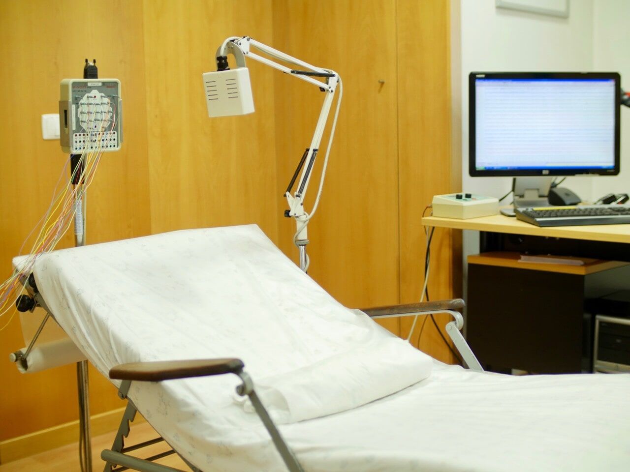 Sala de exames com maca, luz e computador.