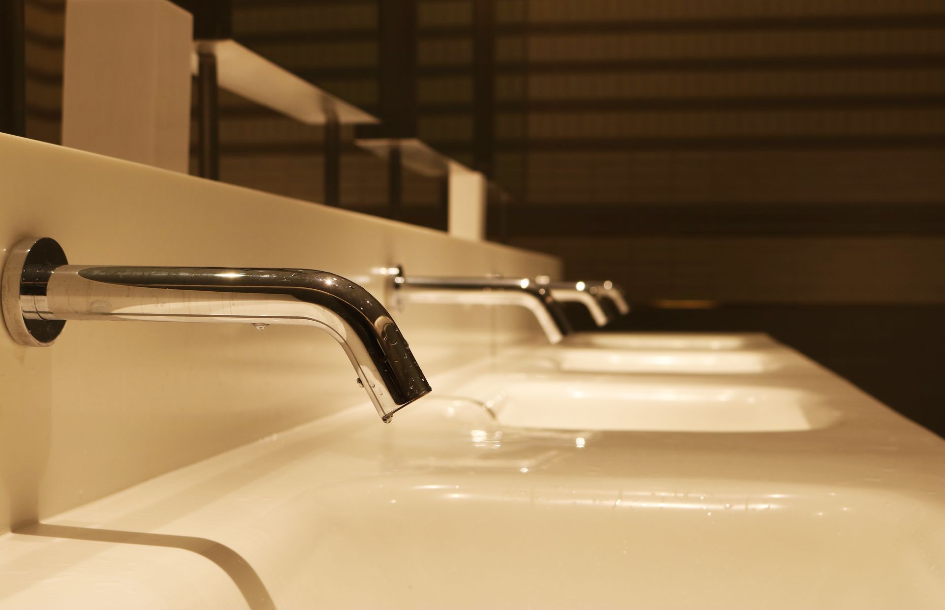 A bathroom with a row of sinks and faucets.