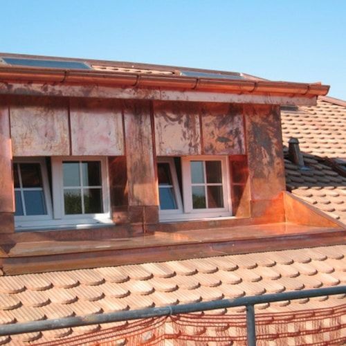 A copper roof with two windows and a solar panel