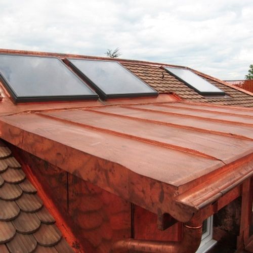 A copper roof with two solar panels on it