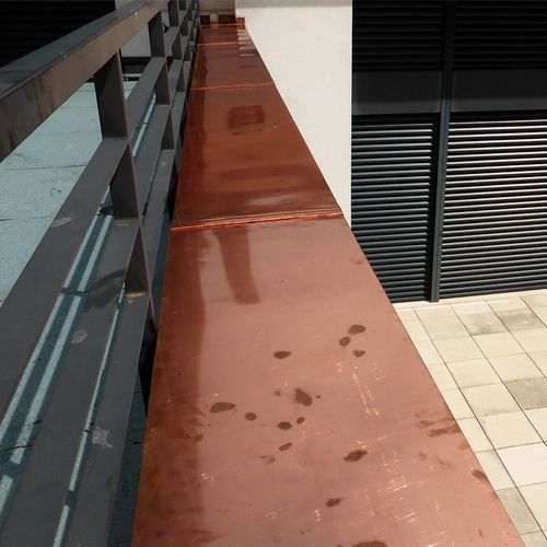 A balcony with a copper railing and shutters