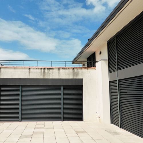 A white house with black shutters on the garage doors.