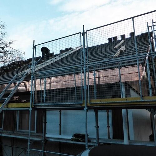 A man is working on the roof of a building with scaffolding
