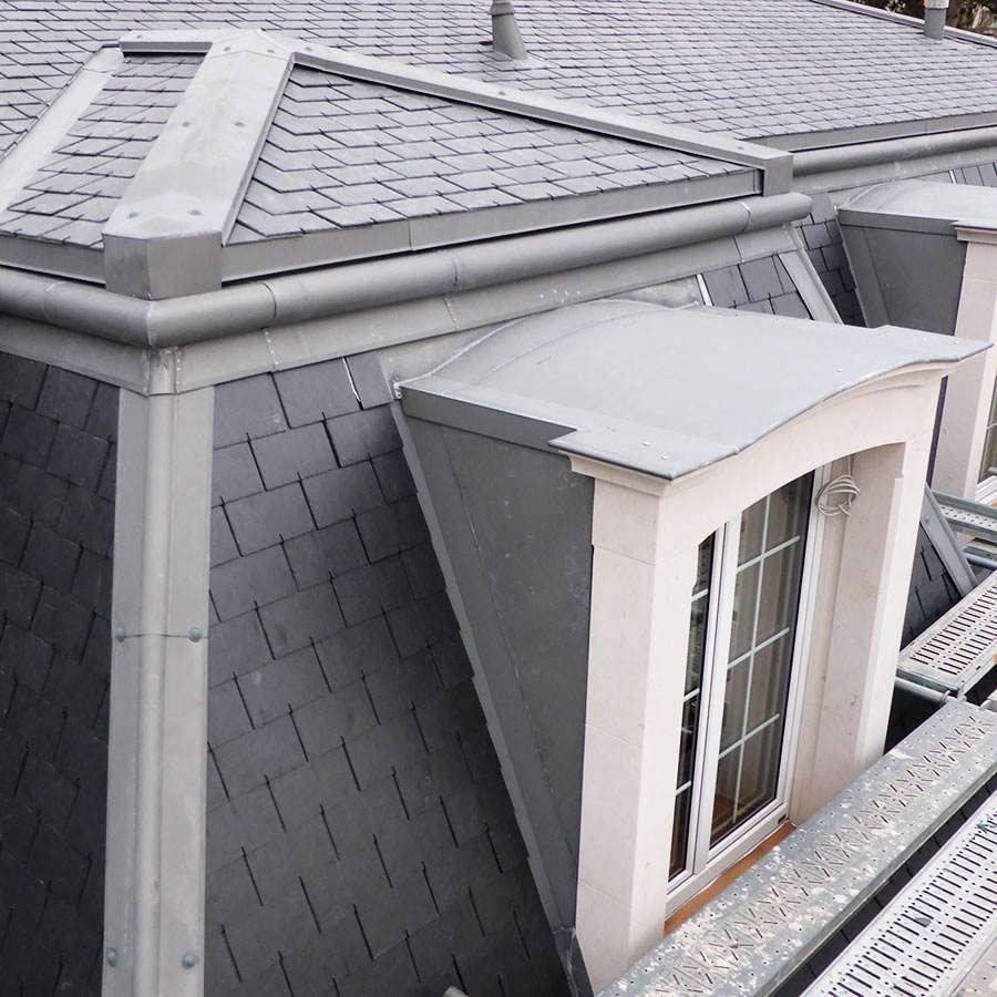The roof of a building with slate tiles and a window
