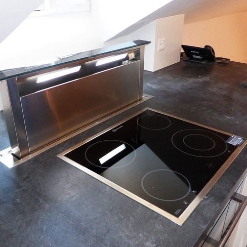 A black stove top with a stainless steel hood