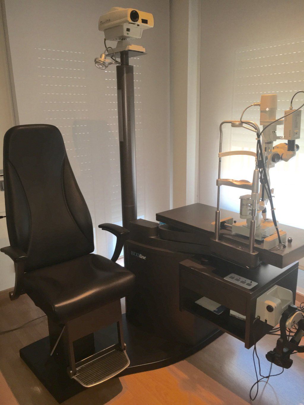 Una silla negra está junto a un microscopio en una habitación.