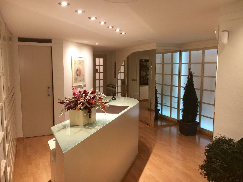 Un mostrador blanco en una habitación con un jarrón de flores encima.