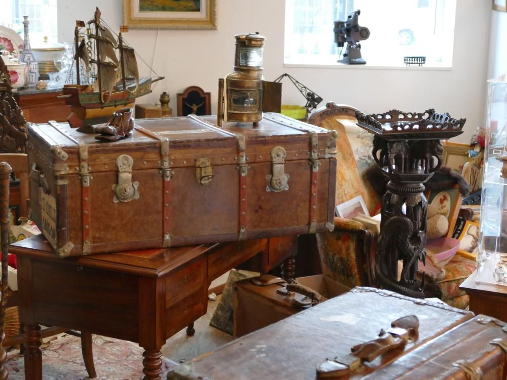 Malles anciennes et décoration vintage dans une pièce avec une maquette de bateau et des meubles en bois ouvragés