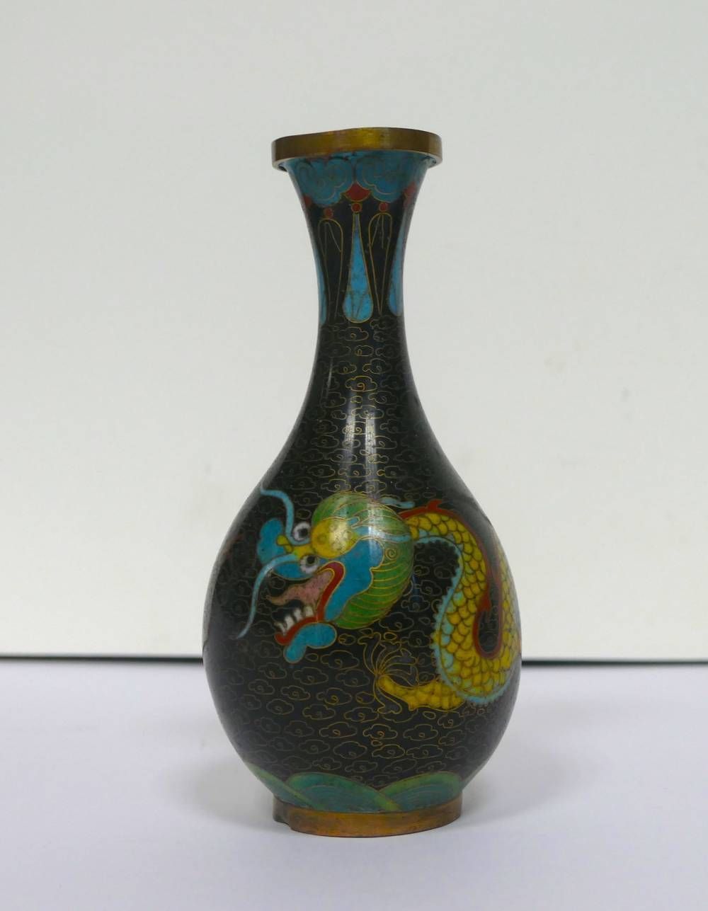 Vase noire ornée d’un motif coloré évoquant un dragon, sur fond blanc uni