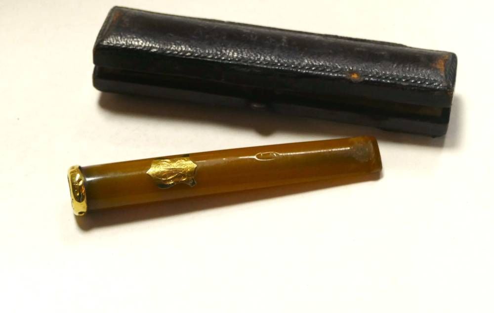 Deux petits tubes cylindriques pour stylo, l’un noir et l’autre ambré, sur fond blanc