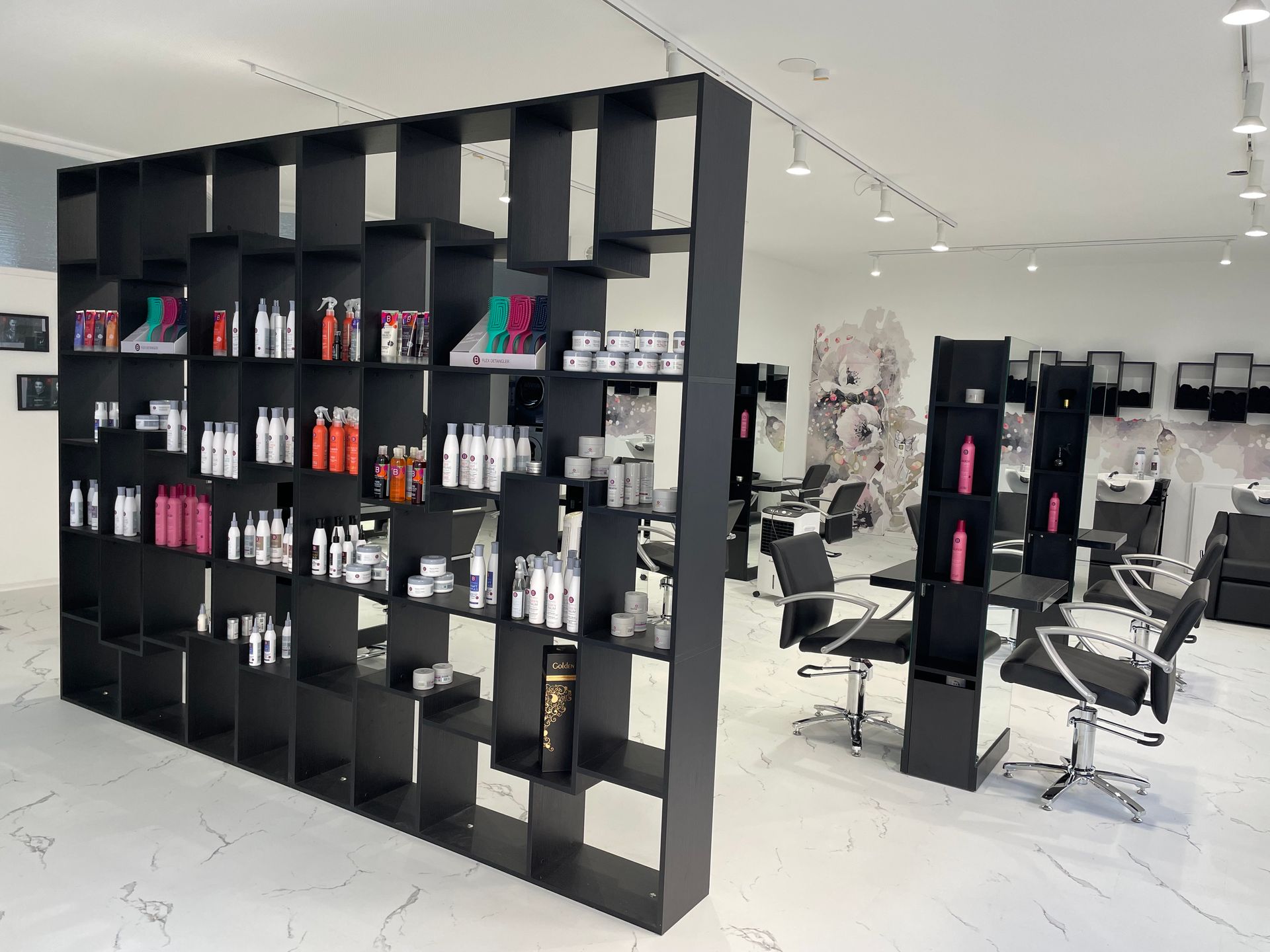 Ein Friseursalon mit schwarzen Regalen und Stühlen.