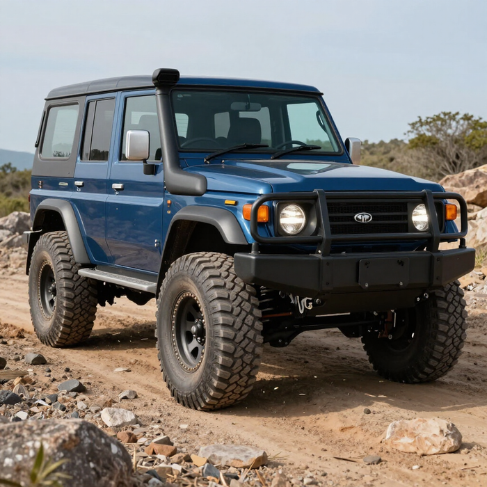 SUV azul todoterreno en terreno rocoso y de tierra con neumáticos grandes y una parrilla protectora negra.
