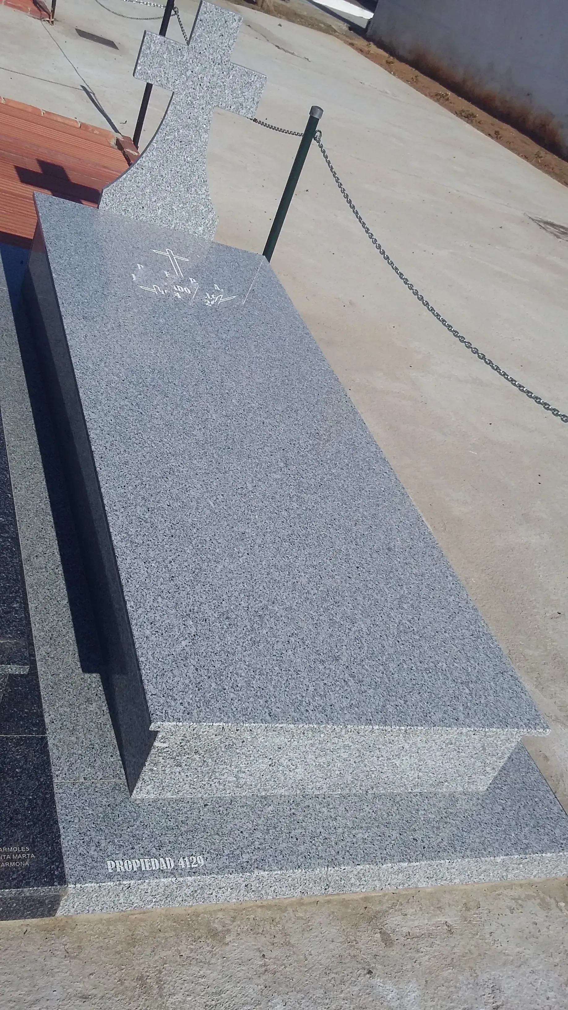 Hay una lápida al costado de la carretera, al lado de una cerca de alambre.