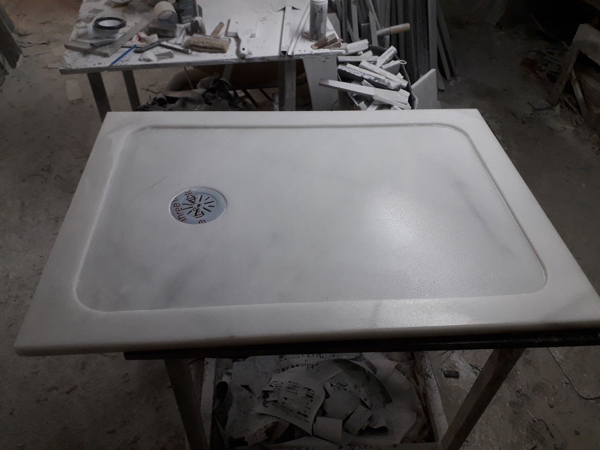 Un plato de ducha blanco está colocado encima de una mesa de madera.