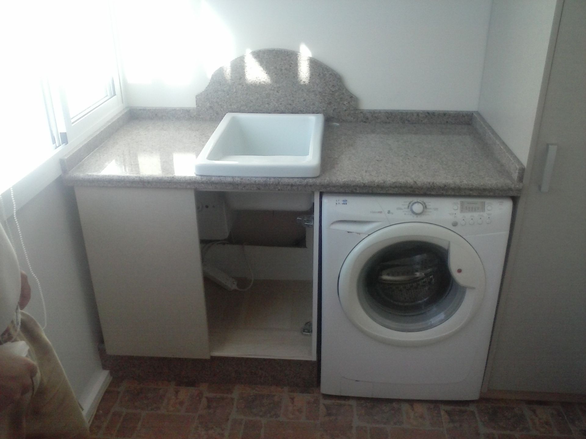 Un lavadero con lavadora y fregadero.