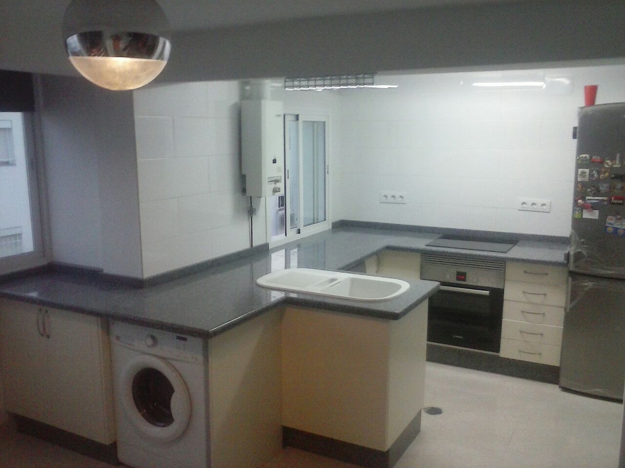 Una cocina con lavadora, secadora y refrigerador.