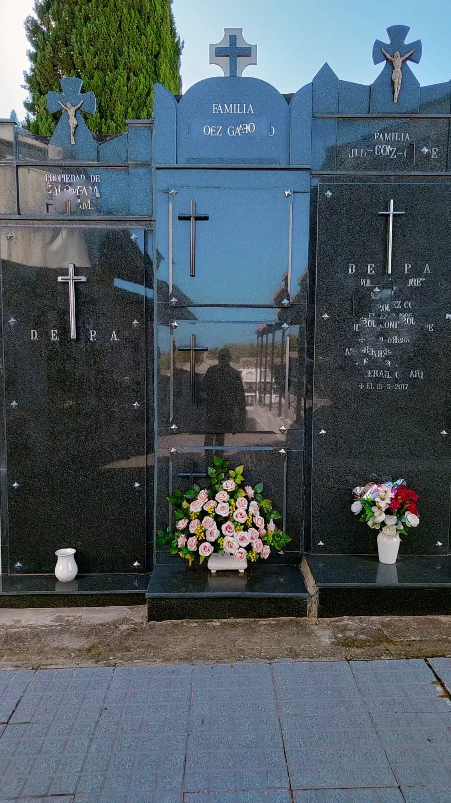 Un cementerio con una cruz y flores en las tumbas.