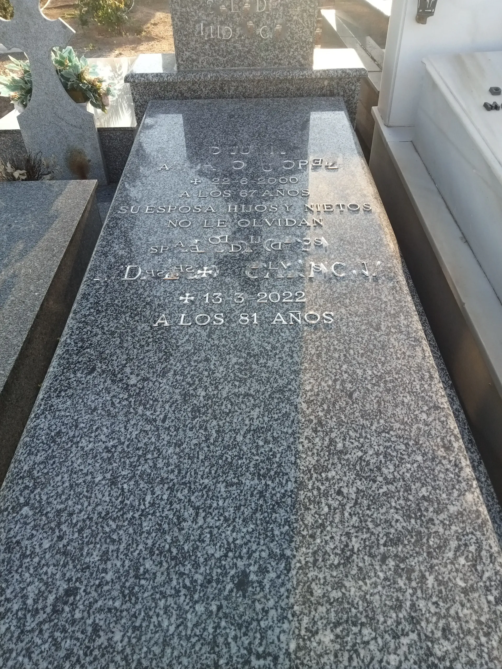 Una lápida en un cementerio con una losa de granito gris.