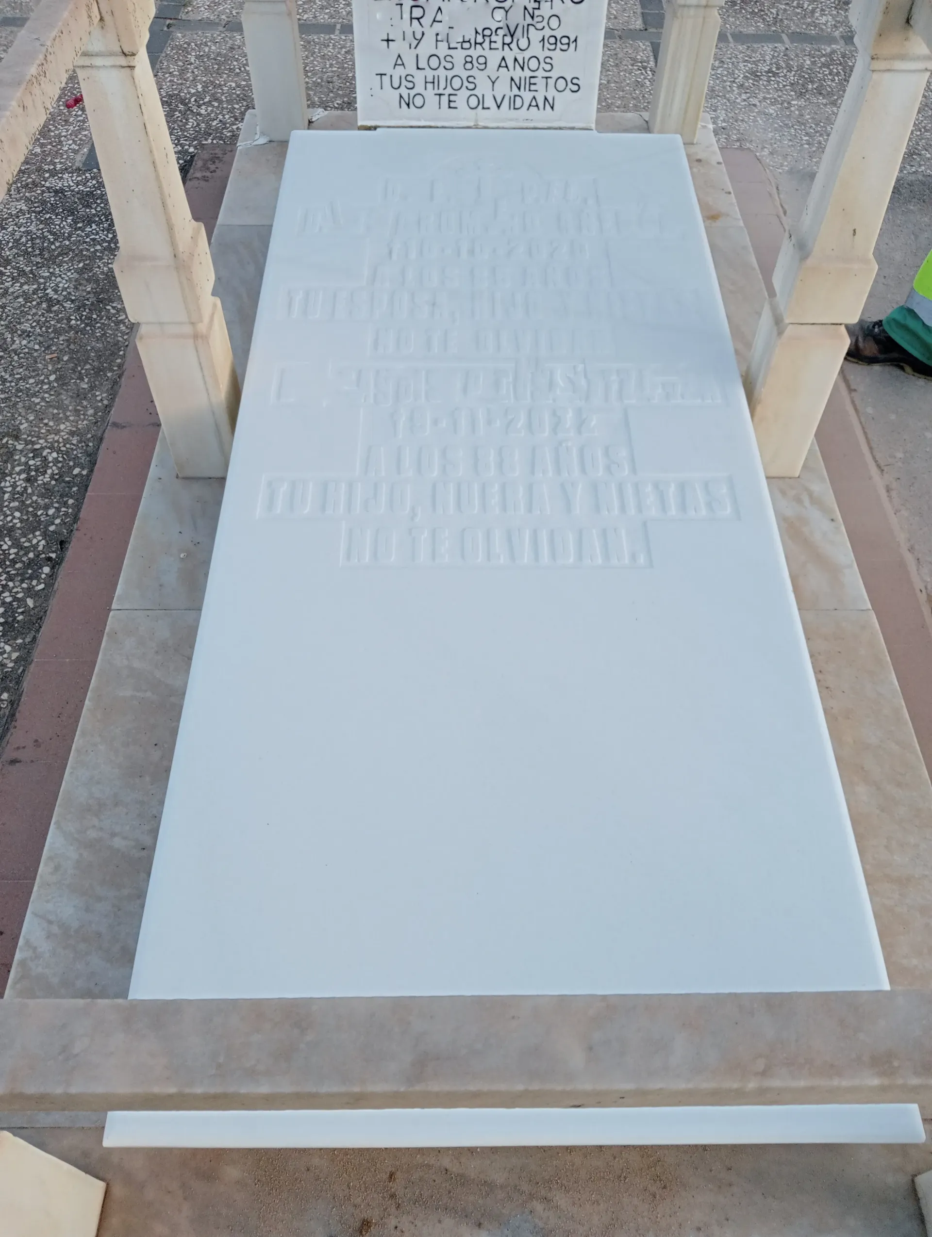 Una lápida blanca se encuentra encima de una tumba en un cementerio.