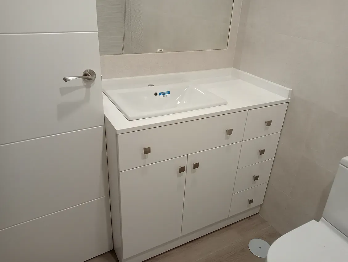 Un baño con lavabo, inodoro y espejo.