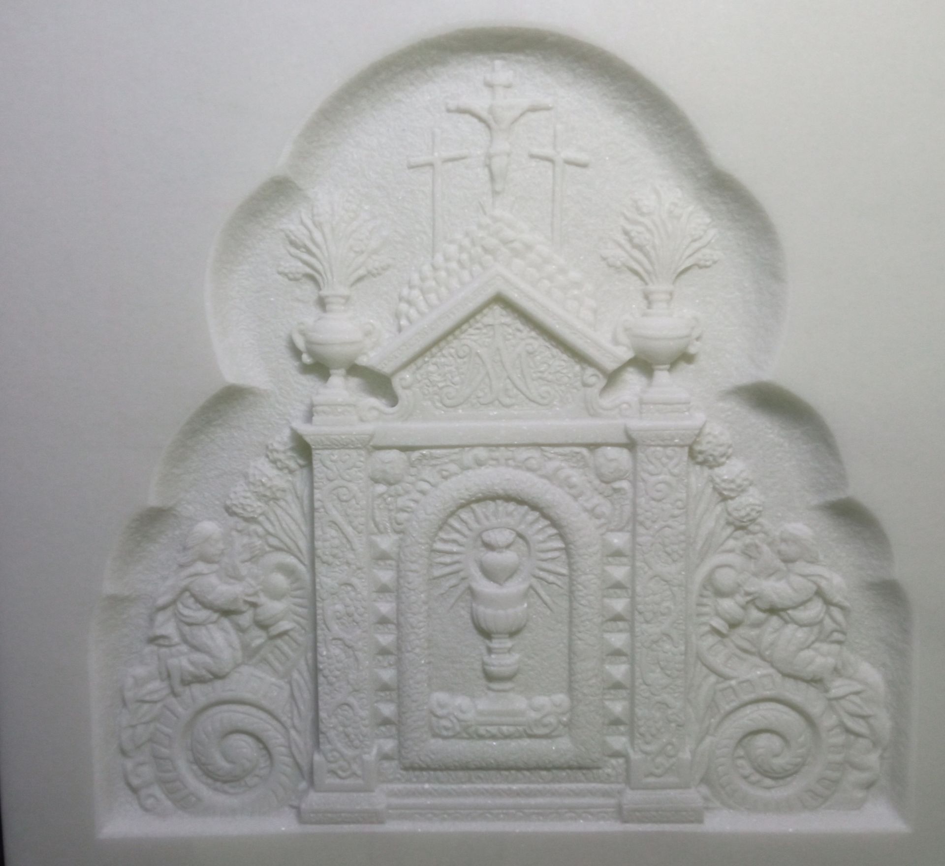 Una talla blanca de una iglesia con una cruz y un cáliz.