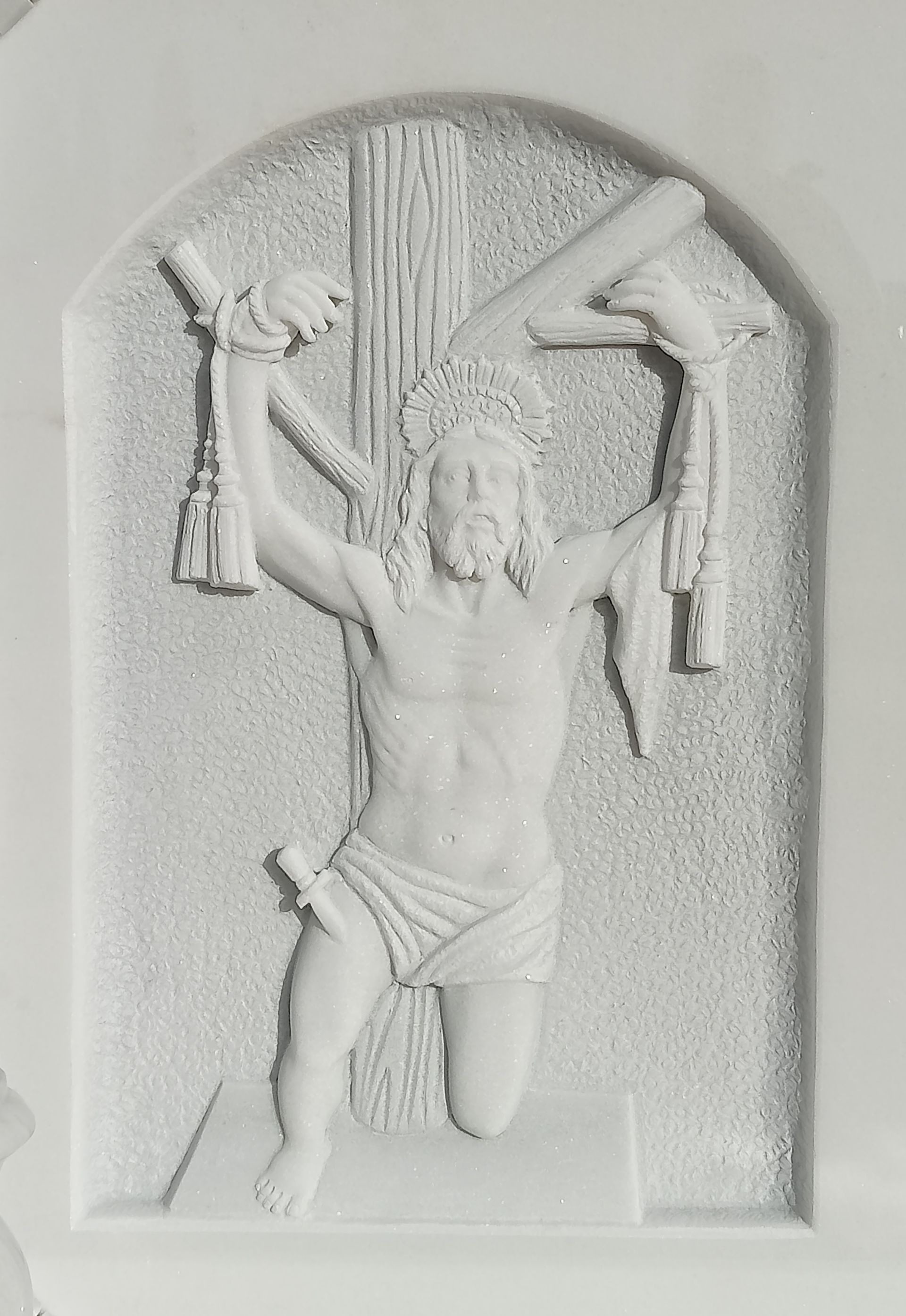 Una estatua blanca de Jesús colgando de una cruz