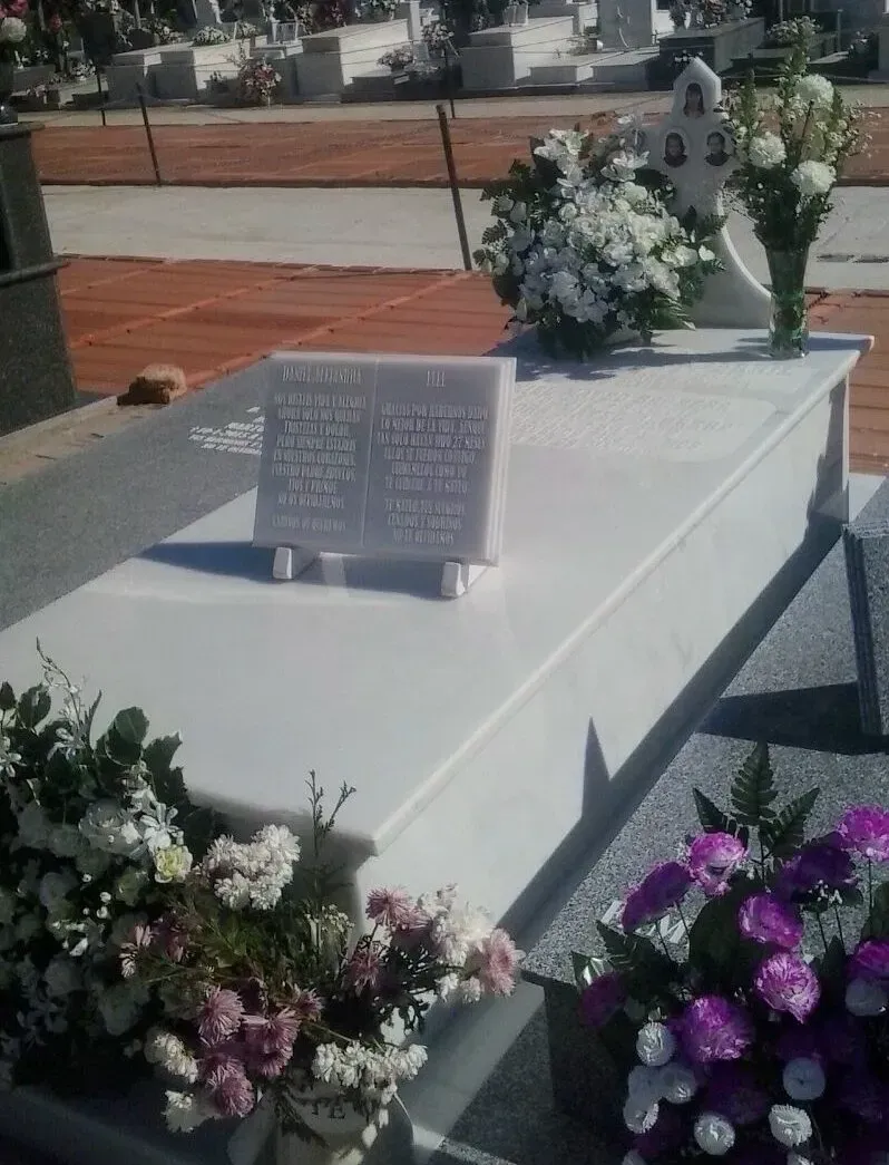 Una tumba en un cementerio con flores y un libro encima.