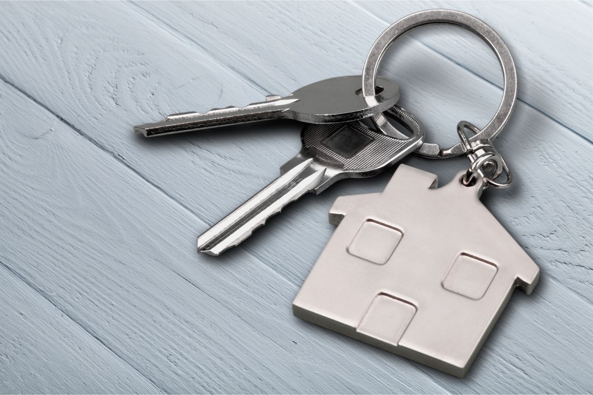 Avaimet, joissa on talon muotoinen avaimenperä vaaleansinisellä puupinnalla.