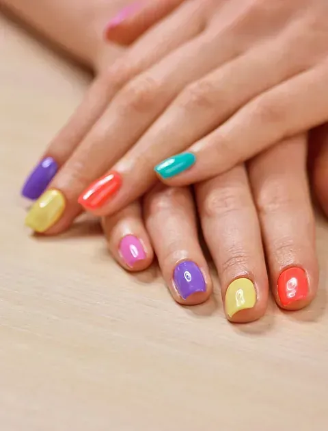 Un primer plano de las manos de una mujer con uñas de colores.