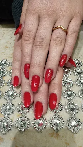 Manos de mujer con uñas rojas y un anillo de oro.