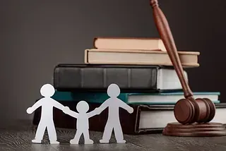 Figuras recortables familiares con libros de leyes y mazo, que representan el derecho de familia.