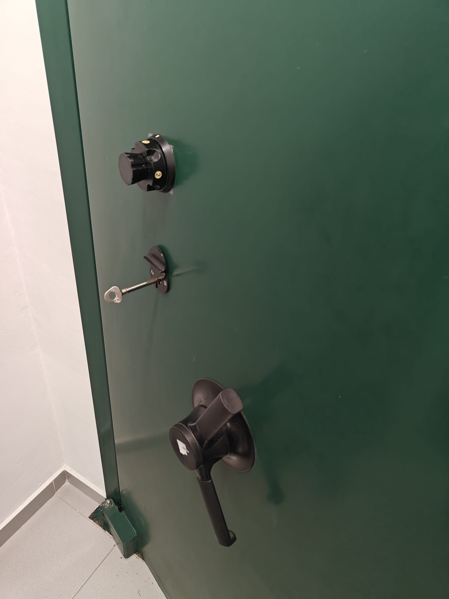 Hombre arrodillado, usando una linterna y un taladro