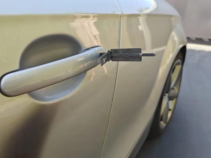 La puerta de un coche se abre con una ganzúa. El coche es de color claro.